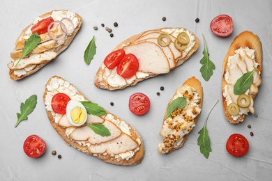 Photo of Different delicious chicken bruschettas on light grey table, flat lay