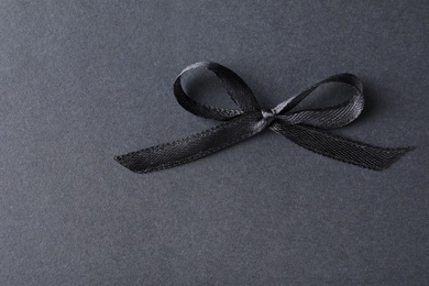 Photo of Black ribbon bow on dark background, above view. Funeral symbol