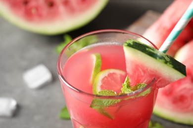 Photo of Glass of tasty refreshing drink with watermelon on grey table, closeup