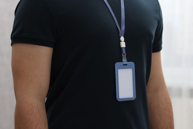 Man with blank badge indoors, closeup view