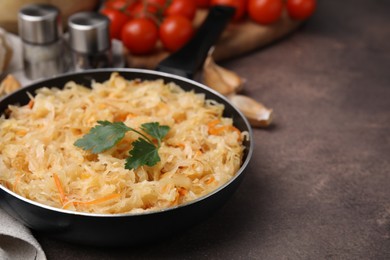 Photo of Frying pan with sauerkraut on brown table, closeup. Space for text