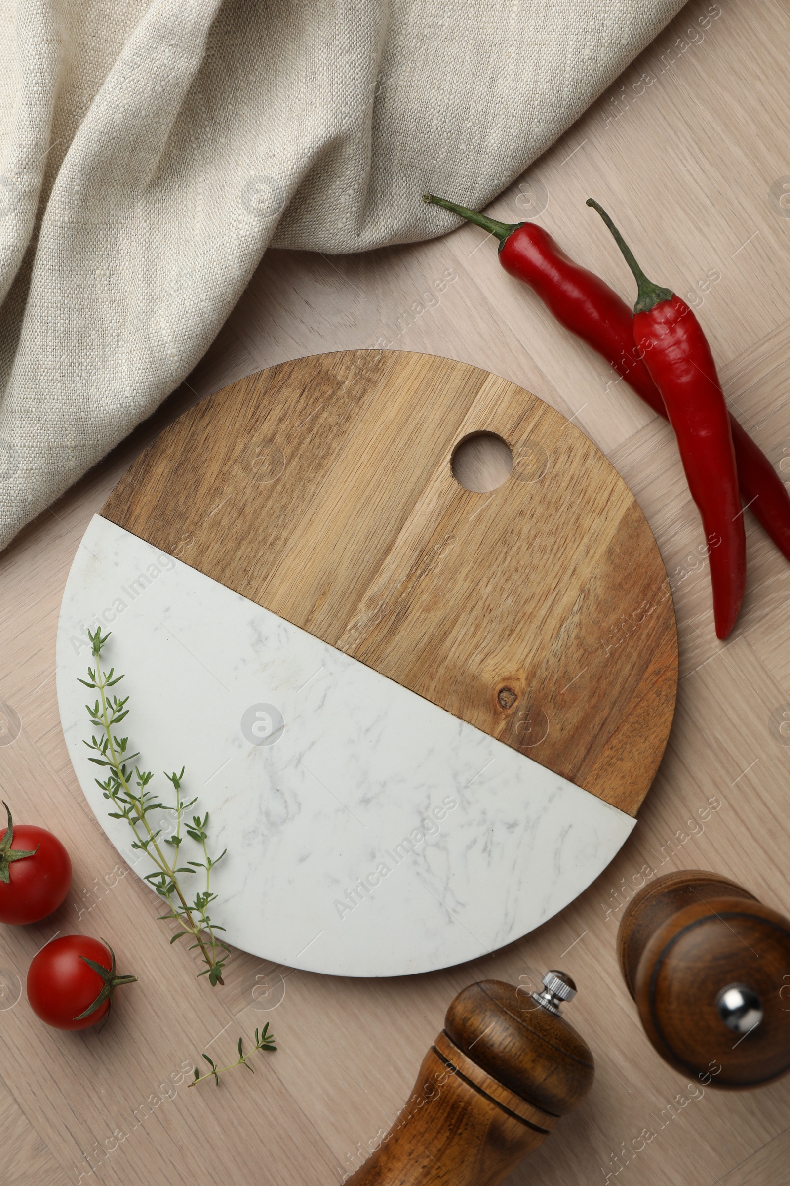 Photo of Cutting board and different spices on wooden table, flat lay