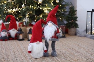 Photo of Cute Scandinavian gnomes on carpet near Christmas tree indoors