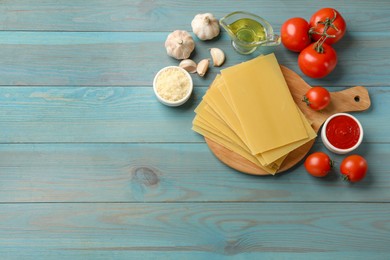 Photo of Ingredients for lasagna on blue wooden table, flat lay. Space for text
