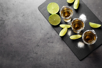 Mexican Tequila shots with salt and lime on grey table, top view. Space for text