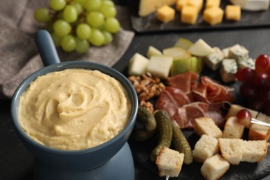 Photo of Fondue with tasty melted cheese and different snacks on table