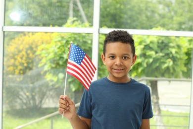 Photo of Happy African-American boy holding national flag near window indoors