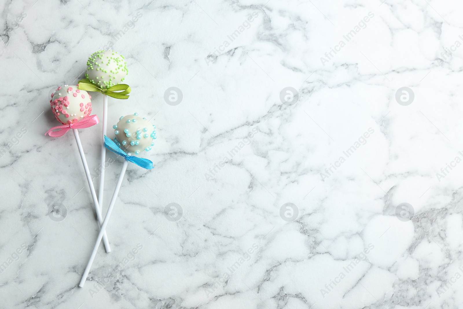 Photo of Different tasty cake pops on white marble background, flat lay. Space for text