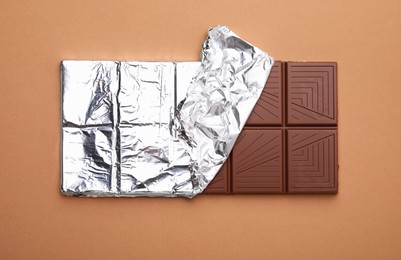 Tasty chocolate bar on brown background, top view