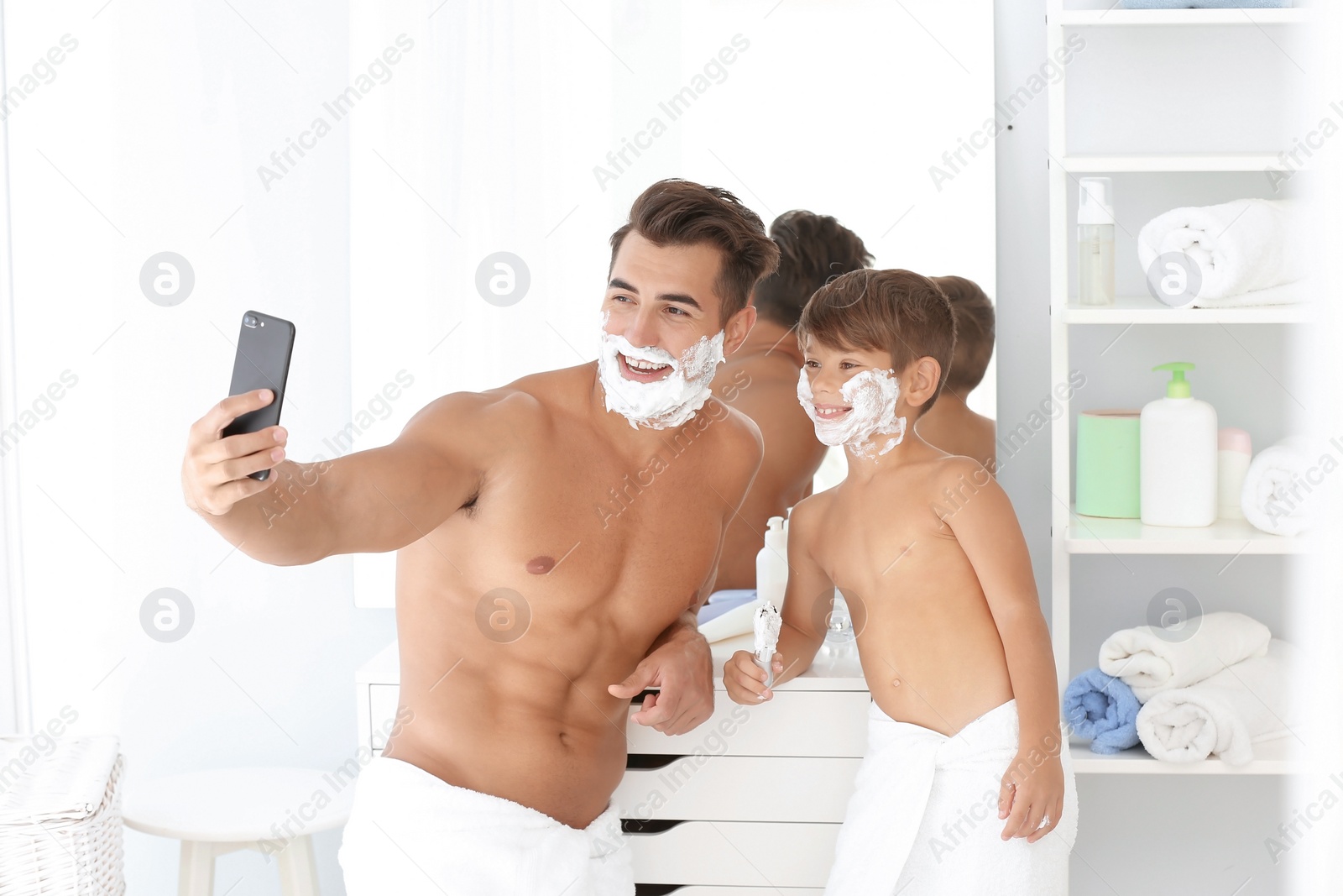 Photo of Father and son taking selfie while shaving in bathroom