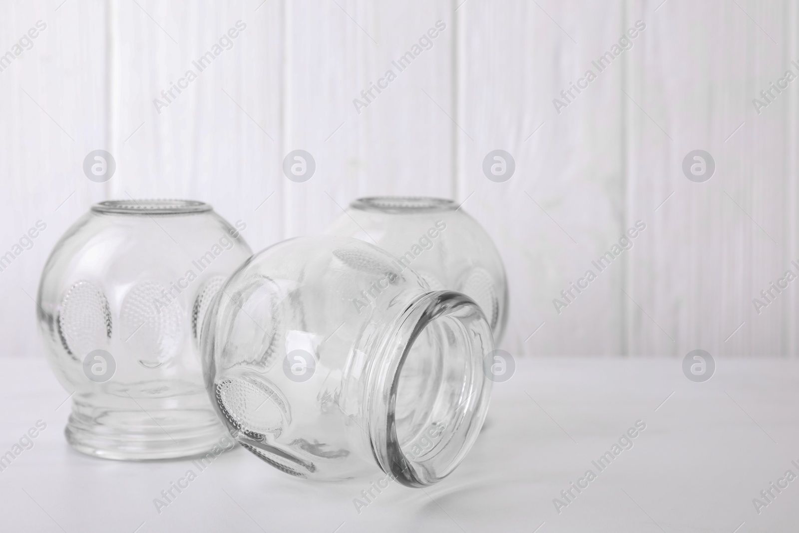 Photo of Glass cups on white table, space for text. Cupping therapy