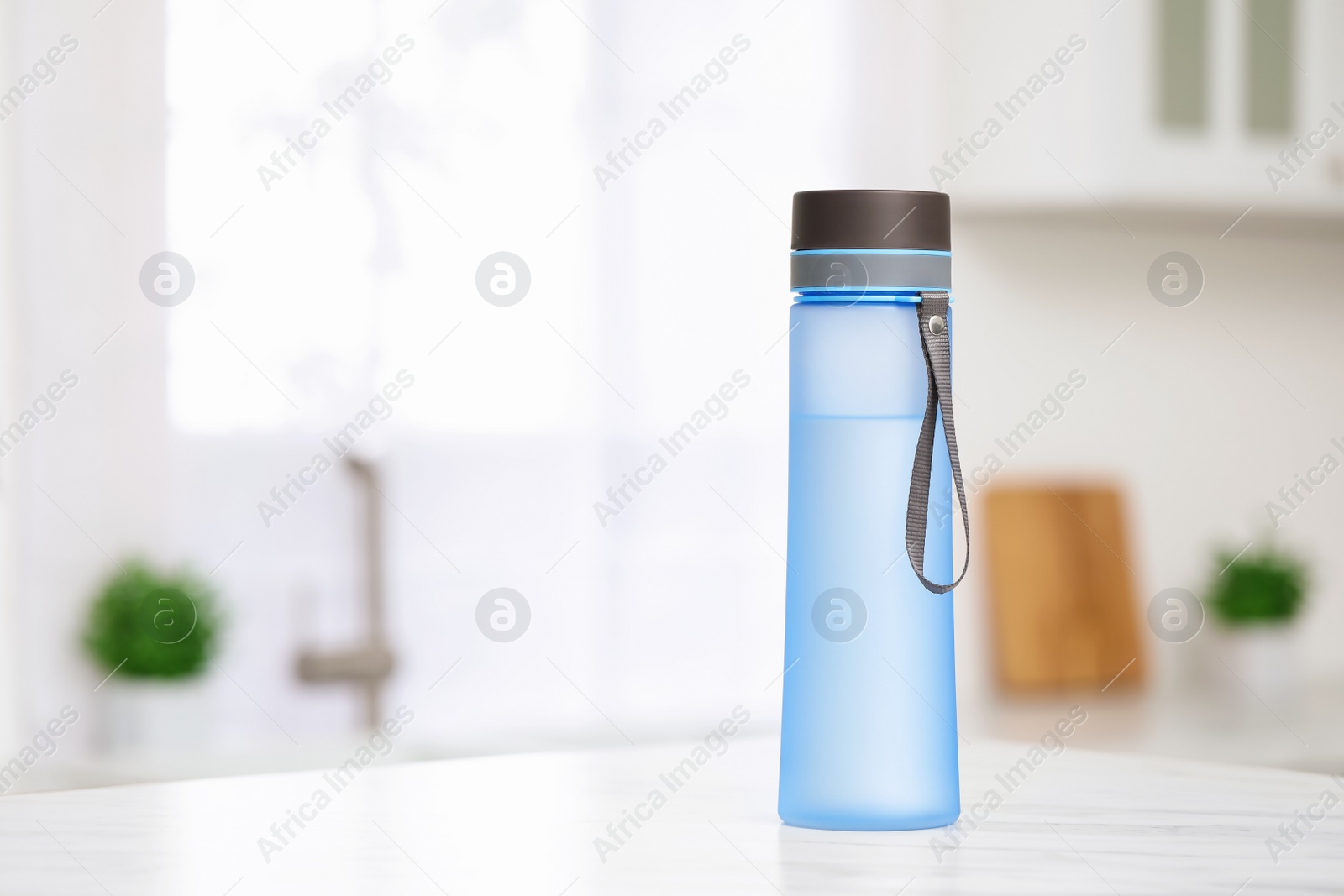 Photo of Stylish bottle of water on table in kitchen. Space for text