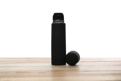 Photo of Stylish thermo bottle on wooden table against white background