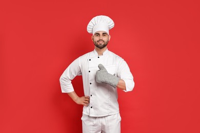 Photo of Professional chef showing thumb up on red background