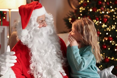 Little girl telling Santa her wish in room with Christmas tree