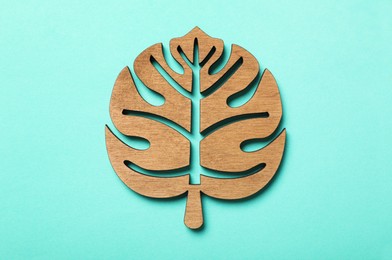 Photo of Leaf shaped wooden cup coaster on turquoise background, top view