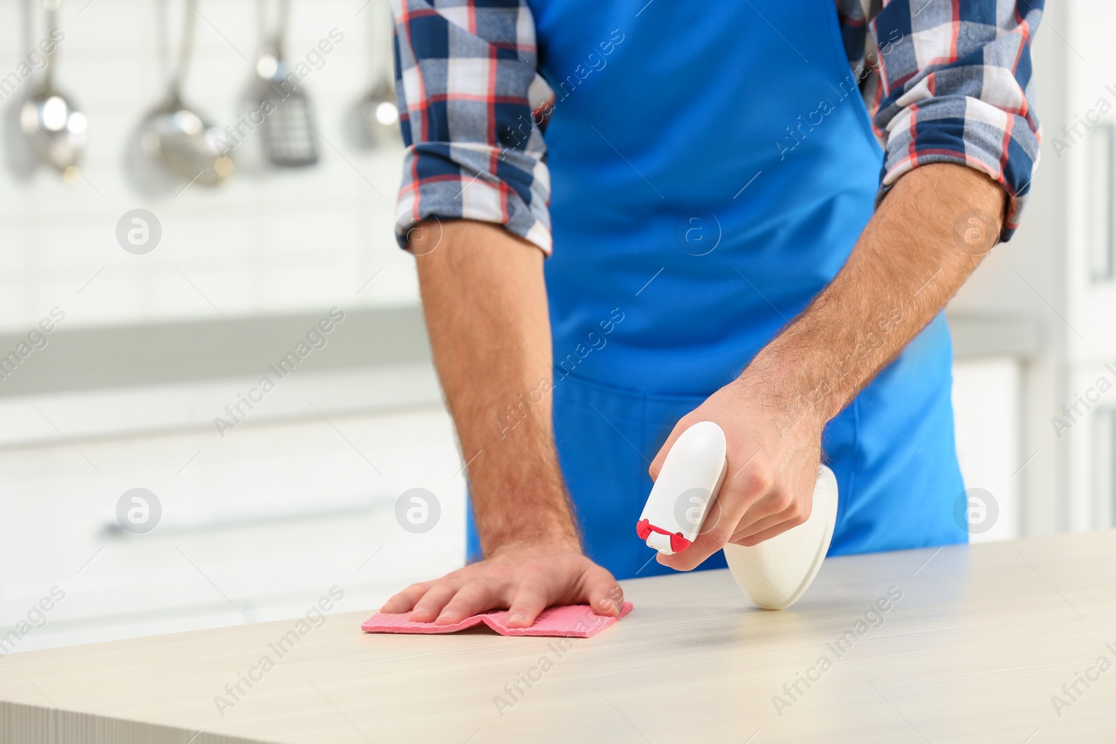 Photo of Man cleaning table with rag in kitchen, closeup