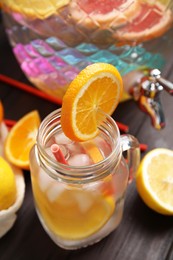 Photo of Delicious refreshing lemonade with orange slices in mason jar on wooden table