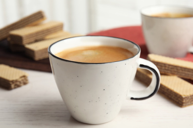 Photo of Delicious coffee and wafers for breakfast on white wooden table