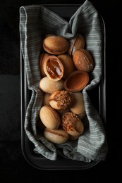 Photo of Freshly baked homemade walnut shaped cookies with condensed milk on black table, top view