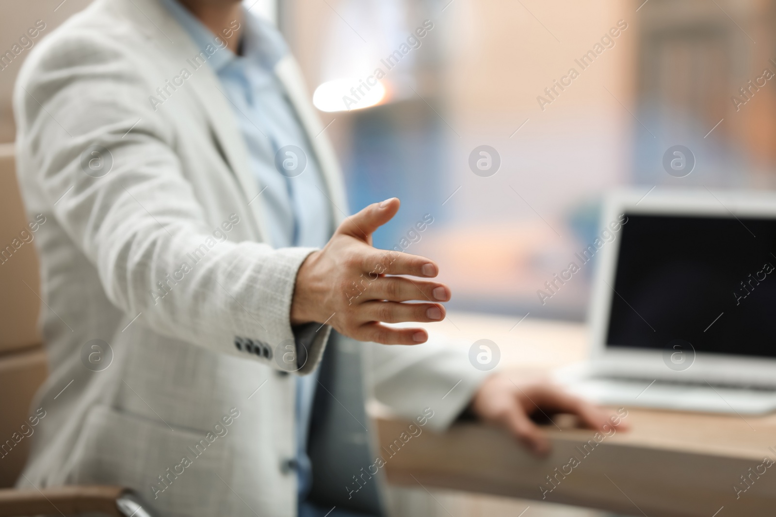 Photo of Businessman offering handshake in office, closeup. Space for text