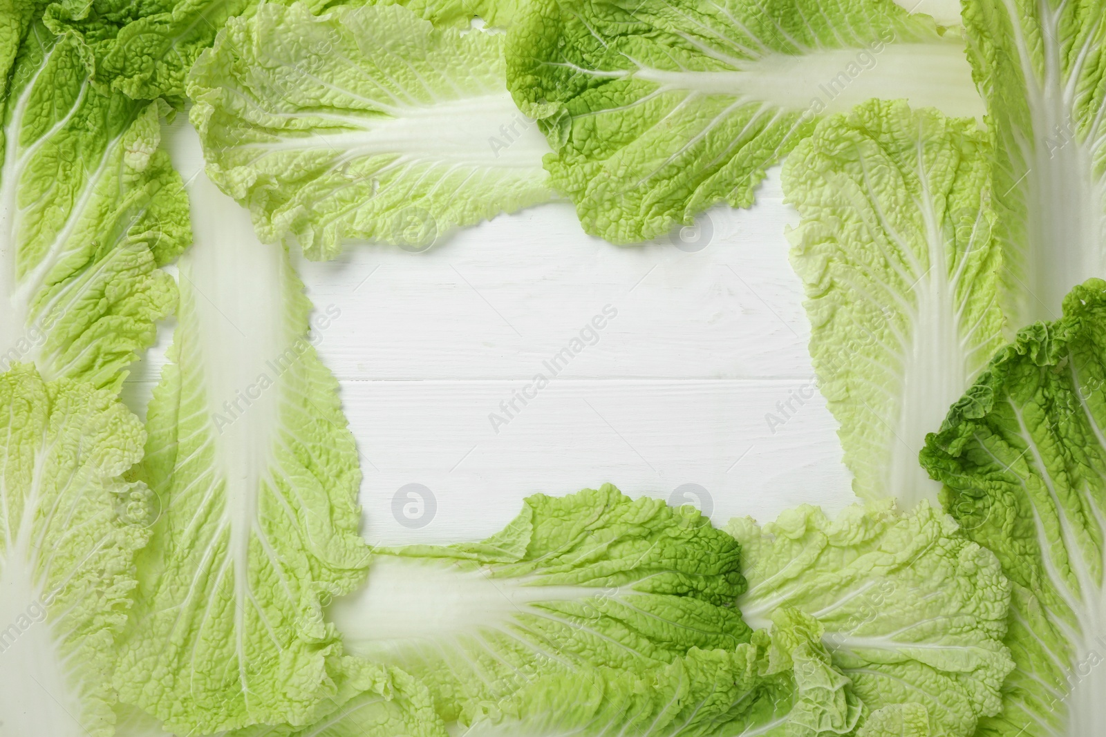 Photo of Frame with fresh ripe leaves of Chinese cabbage on white wooden table, flat lay. Space for text