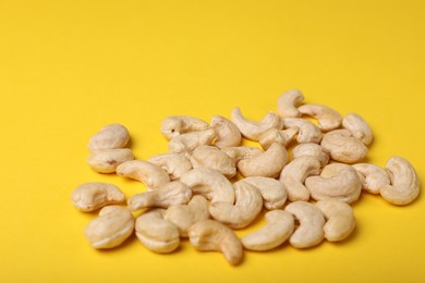 Photo of Tasty cashew nuts on yellow background, closeup