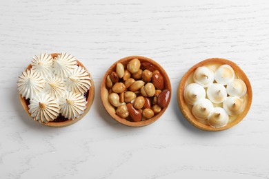 Different tartlets on white wooden table, flat lay. Delicious dessert