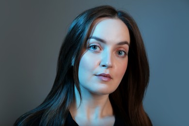 Portrait of beautiful young woman on color background with neon lights