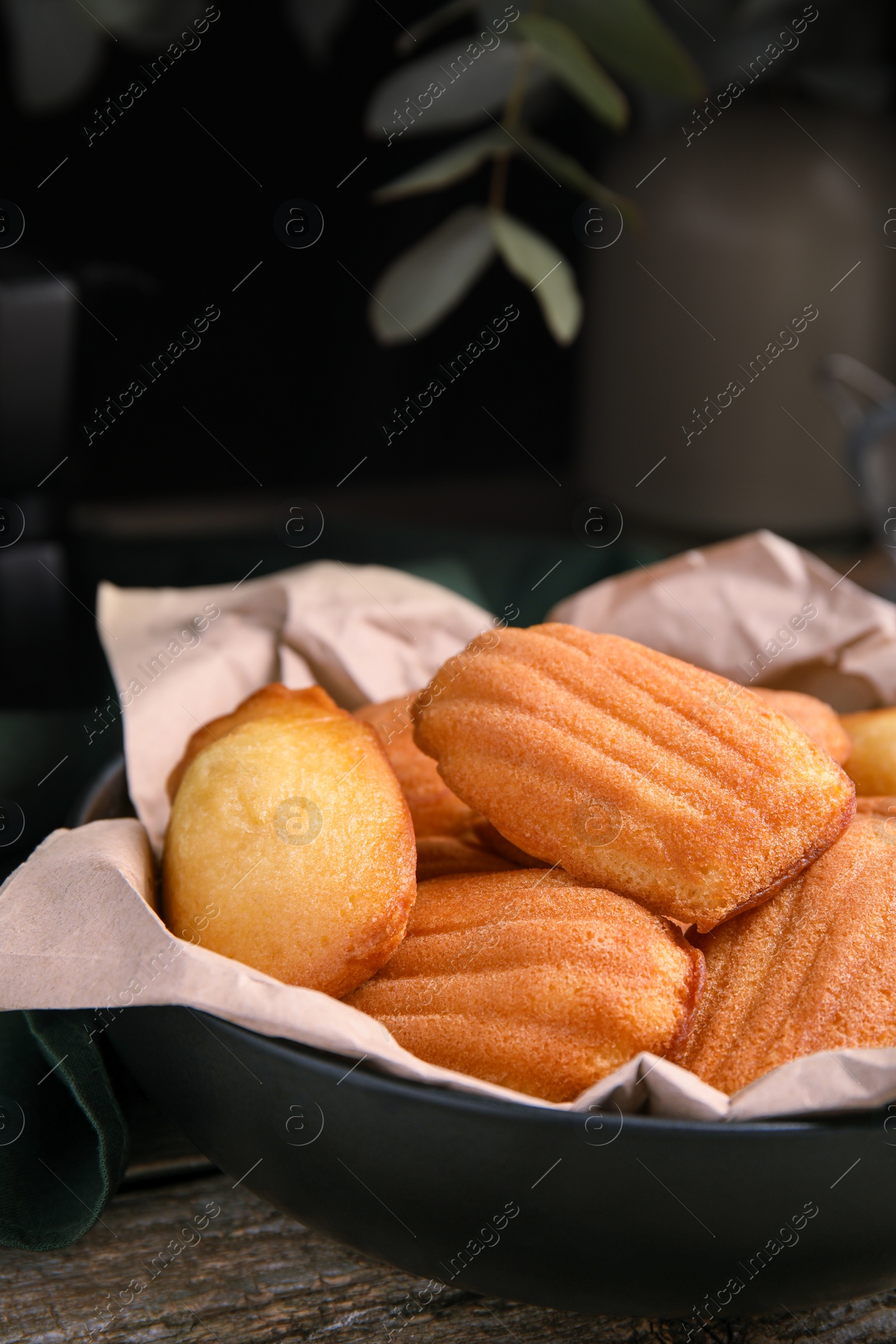 Photo of Delicious madeleine cakes in bowl on wooden table, closeup