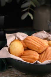 Delicious madeleine cakes in bowl on wooden table, closeup