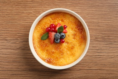 Delicious creme brulee with fresh berries on wooden table, top view