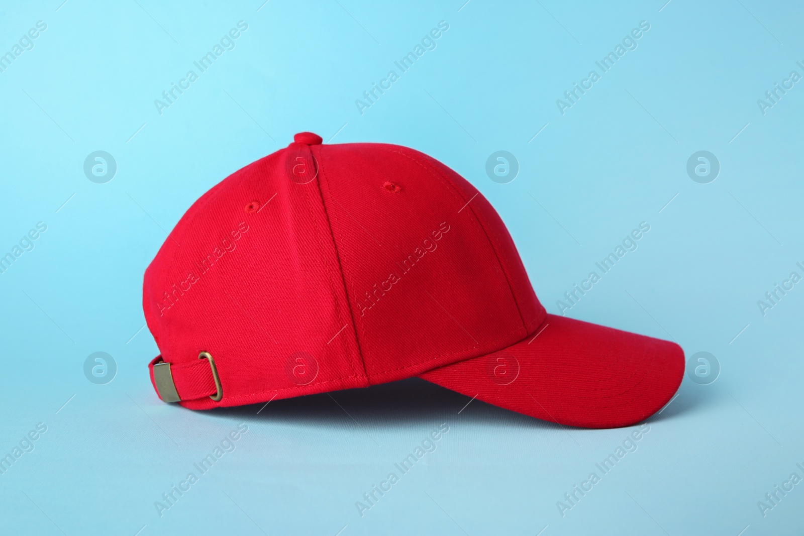 Photo of Stylish red baseball cap on light blue background