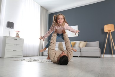 Photo of Father and his daughter having fun at home. Floor heating concept