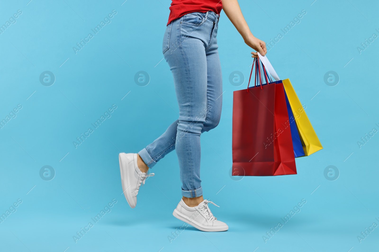 Photo of Woman with shopping bags on light blue background, closeup. Space for text