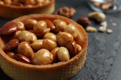 Tartlet with caramelized nuts on black slate, closeup. Delicious dessert