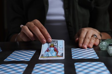 Photo of Fortune teller predicting future on spread of tarot cards at grey table, closeup