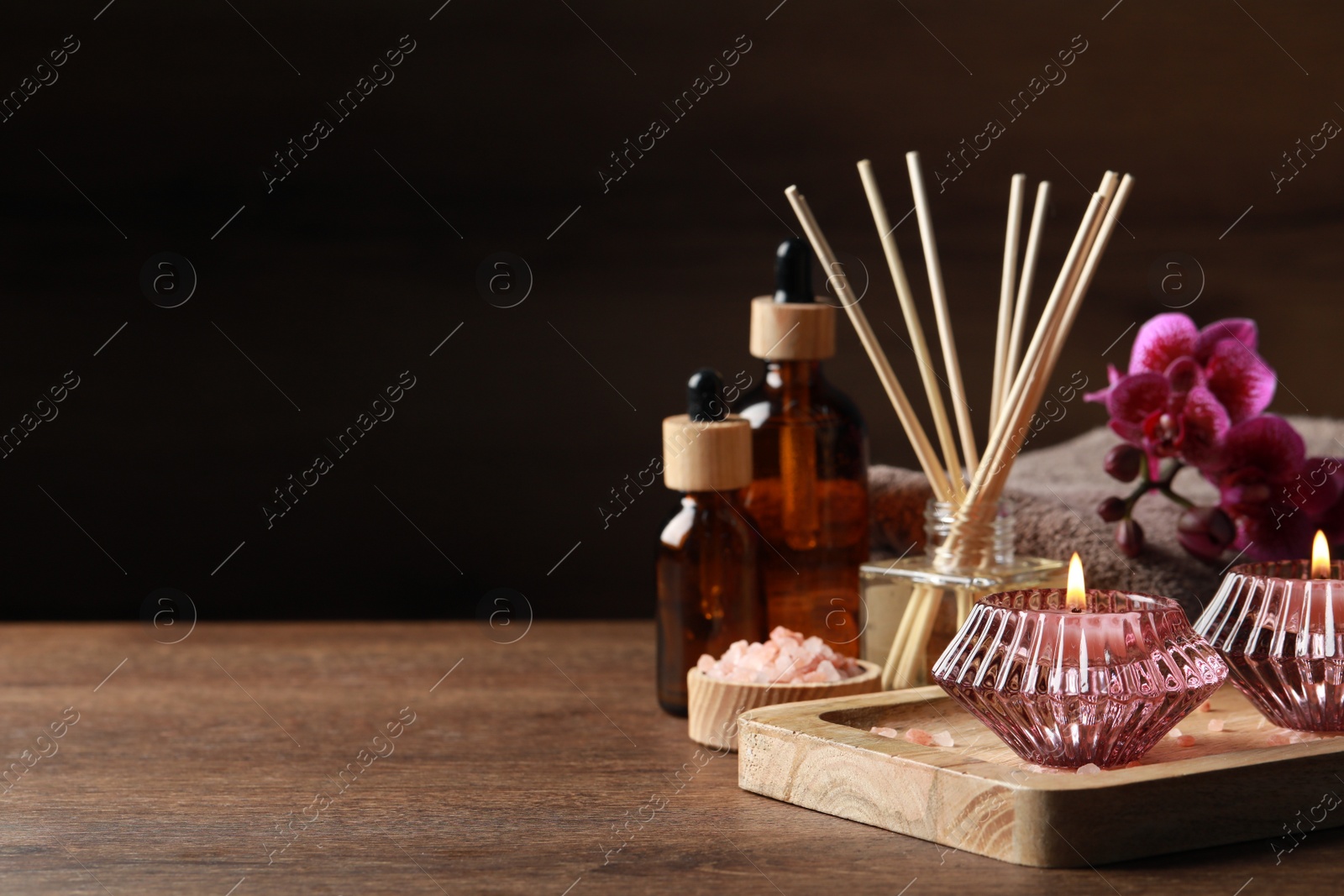 Photo of Beautiful spa composition with different care products and burning candles on wooden table. Space for text