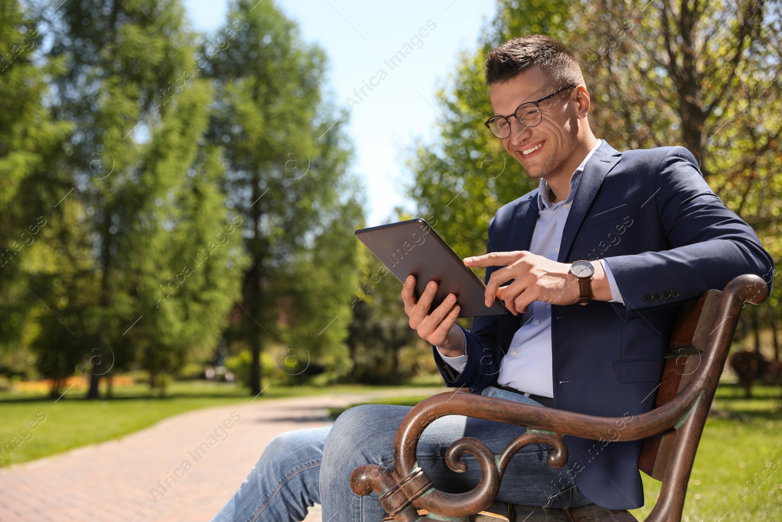 Photo of Man working with tablet on bench in park