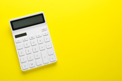 Photo of Modern calculator on yellow background, top view. Space for text