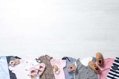 Photo of Flat lay composition with cute baby clothes and shoes on white wooden background. Space for text