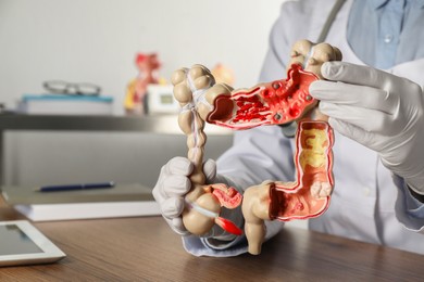 Photo of Gastroenterologist with human colon model at table in clinic, closeup