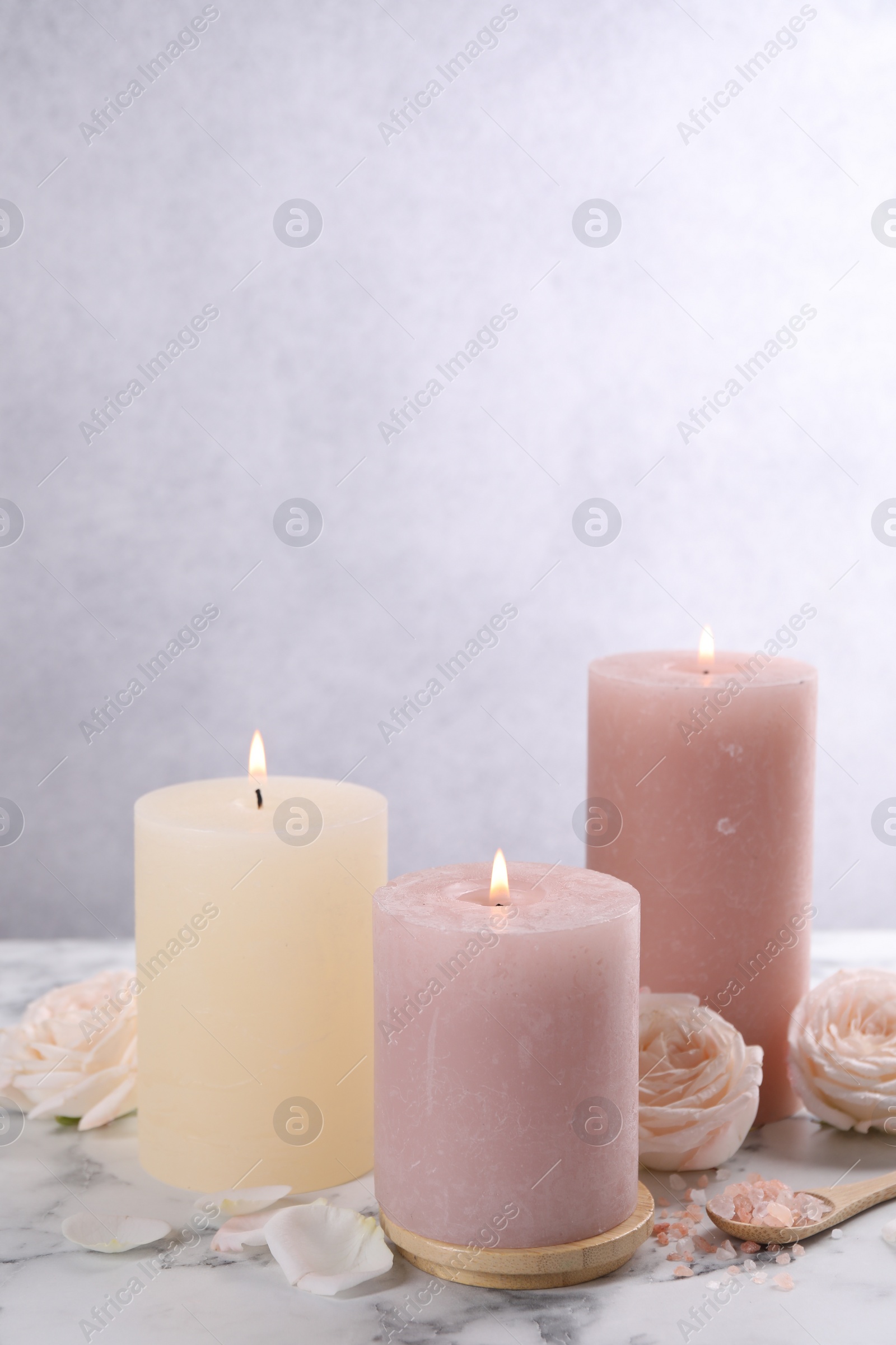 Photo of Spa composition with burning candles, flowers and sea salt on white marble table