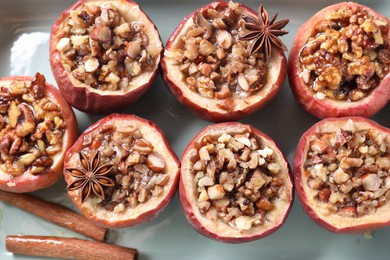 Photo of Tasty baked apples with nuts, honey and spices in dish, closeup