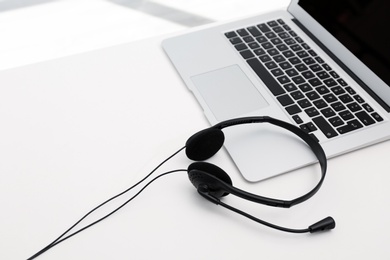 Photo of Modern laptop and headset on table. Technical support concept