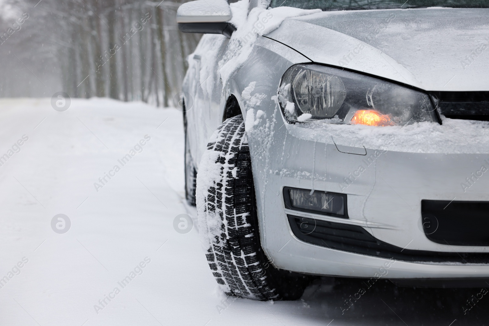 Photo of Car with winter tires on snowy road in forest, space for text