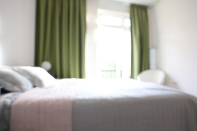 Photo of Blurred view of large bed near window in room