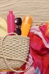 Flat lay composition with wicker bag and other beach accessories on sand