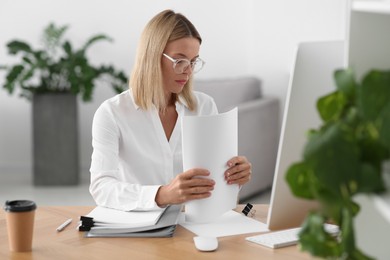 Woman working with documents at wooden table in office