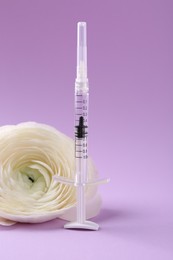 Photo of Cosmetology. Medical syringe and ranunculus flower on violet background